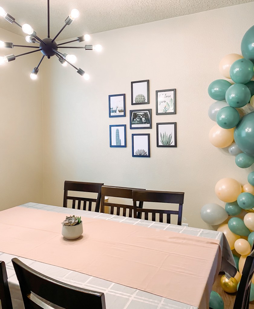 A table with a white table cloth, pink chiffon table runner, and a succulent centerpiece. 