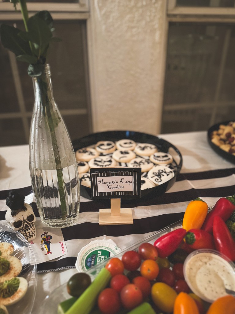 A vegetable platter and a platter of Jack Skellington sugar cookies with a sign that reads "Pumpkin King Cookies."