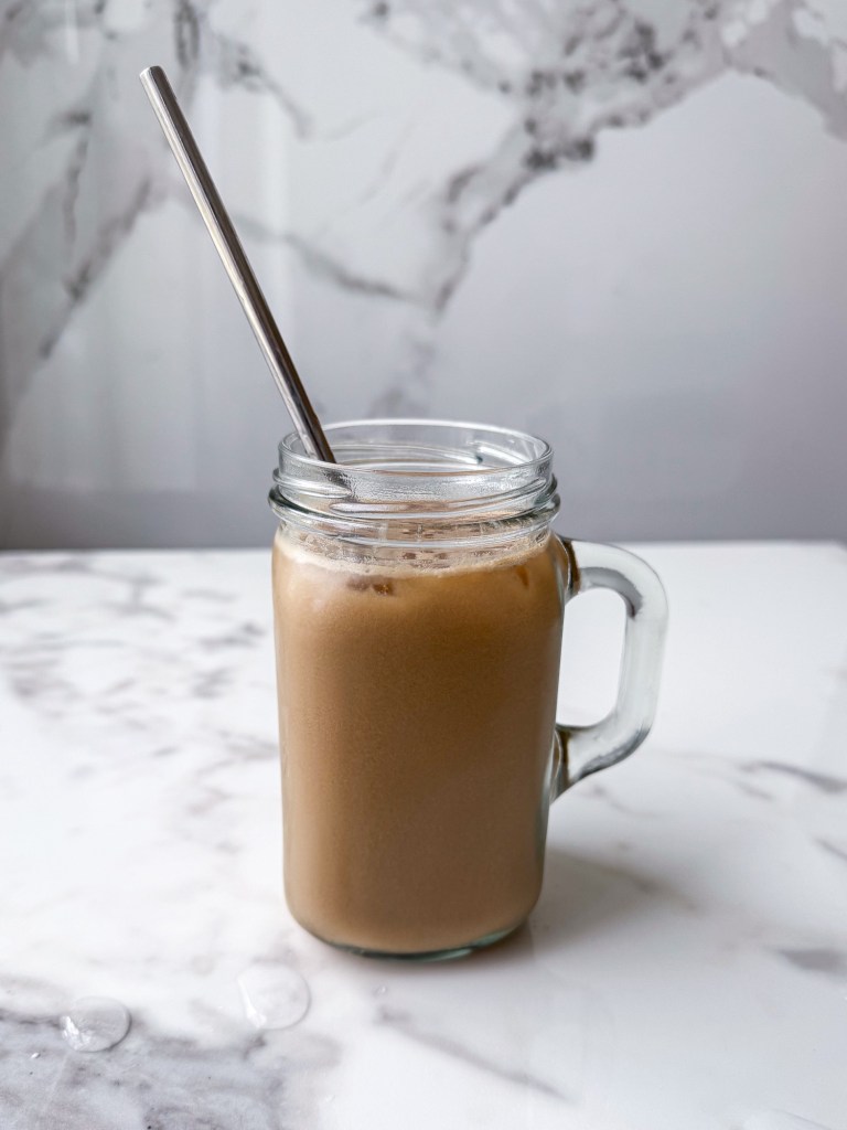 glass mason jar mug filled with a copycat version of Swig's Dirty Little Secret Drink: Dr Pepper Zero, coconut syrup, pineapple juice, vanilla creme, and ice.